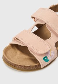 Rosa Veloursledersandale mit zwei verstellbaren Riemen, Korksohle und besticktem Blumendetail im Zehenbereich.