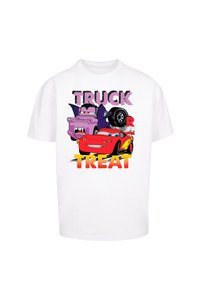 Hvid t-shirt med et farverigt grafik af tegneserie-biler: en lilla lastbil og en rød racerbils, med teksten "TRUCK OR TREAT" i fede, multifarvede skrifttyper.
