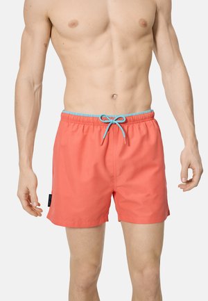 Torso masculino sin camisa con pantalones cortos de baño coral con cordón azul claro, de pie contra un fondo liso.