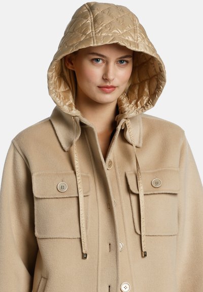 Cappotto in misto lana beige con cappuccio trapuntato beige, dotato di due tasche e chiusura a bottoni, texture liscia e lacci regolabili.