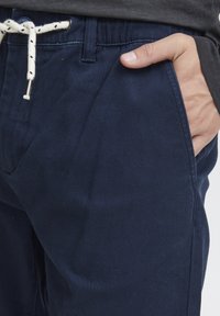 Pantalons en coton bleu marine avec une ceinture à cordon de serrage et des accents crème, des poches latérales et une texture douce.