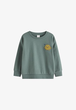 Green sweatshirt made of soft fabric, featuring a round neckline and long sleeves. An embroidered yellow character with a smiling face is on the front.