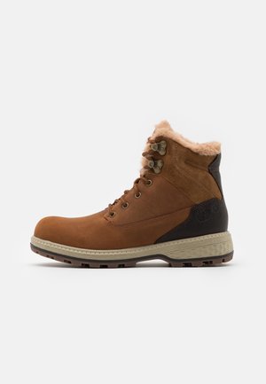 Bota de senderismo marrón con parte superior de ante, cuello de piel sintética y ojales metálicos. Suela de goma texturizada con un dibujo pronunciado para mayor tracción.