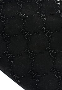 Materiale di suede nero con un motivo testurizzato di piccoli chiodi neri scintillanti disposti in un design a spirale.