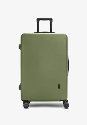 Valigia rigida di colore verde oliva. Superficie liscia, forma rettangolare, manico telescopico nero e quattro ruote nere per la mobilità.