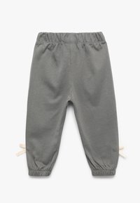 Szare dresowe spodnie z bawełny z elastycznym pasem i białymi akcentami sznurków. Manżety przy kostkach tworzą zwężający się kształt. Miękka struktura.