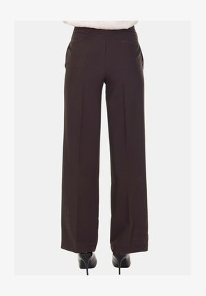 Pantaloni a gamba larga marrone scuro con una texture liscia, pieghe discrete e due tasche posteriori. Abbinati a scarpe col tacco nere.