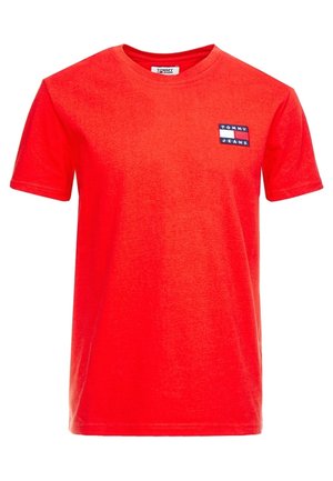 Rotes Baumwoll-T-Shirt mit Rundhalsausschnitt. Verfügt über ein kleines navy-weißes „TOMMY JEANS“ Logo-Patch auf der linken Brust. Glatte Textur.