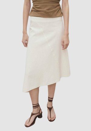 A linen midi skirt in off-white, featuring an asymmetric hem, subtle diagonal seam, and paired with brown strappy sandals.