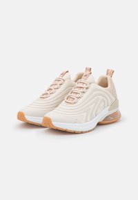Beige sneakers with textured synthetic upper, laced design, orange accents, and a clear air cushion sole. Rubber outsole for traction.