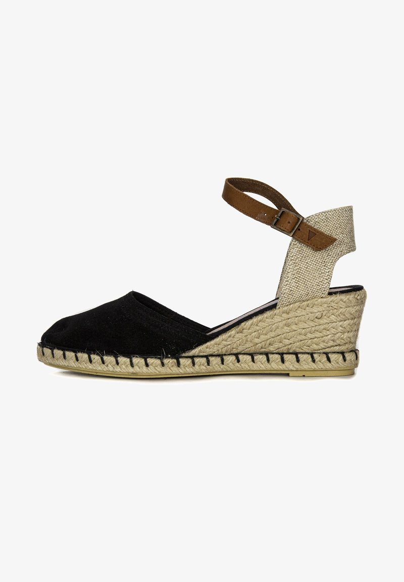 Zwarte canvas espadrille met een wiggenhak, beige textiele enkelband en geweven jute detail rond de zool. Verstelbare gesp sluiting.