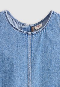 Light blue denim top with a round neckline, featuring visible stitching, a central seam, and a red brand label at the back.