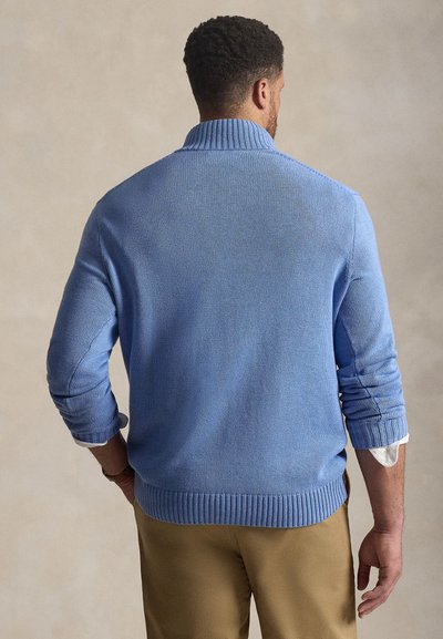 Ανοιχτό μπλε πλεκτό πουλόβερ με ψηλό γιακά, ριμπ μανσέτες και τελείωμα. Διαθέτει υφή υφάσματος και ελαφρώς γυρισμένα μανίκια.