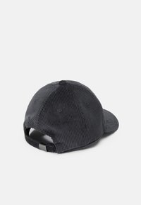 Gorra de pana negra con visera curvada, costuras visibles, ojales de ventilación y una correa ajustable en la parte posterior.