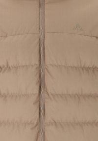 Beige puffer väst med horisontellt kviltade sektioner, en framdragkedja och en diskret logotyp. Materialet verkar slätt med en lätt glans.