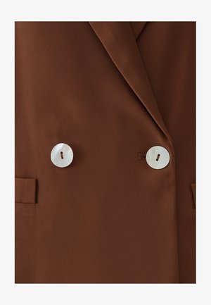 Brown blazer with a smooth texture, double-breasted design, and two large white button fastenings. Features tailored lapels and side pockets.