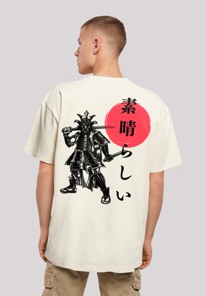 Cream oversized t-shirt featuring a black samurai graphic and red circle on the back. Cotton material with a smooth texture.