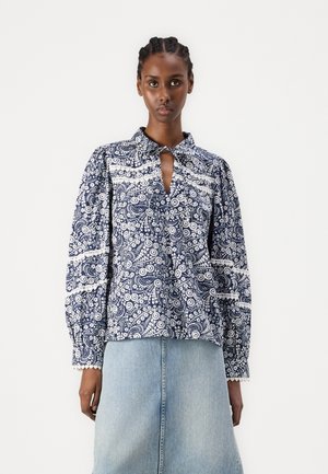 Løsgående marineblå bluse med hvitt blomsterdesign, kragehals og nøkkelhullsdetalj foran. Lange puffermer og blondekant.