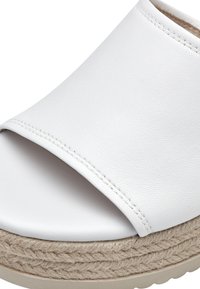 Witte faux leren slip-on sandaal met een brede bovenband, een jute gewikkelde platformzool en een textuur afwerking op het materiaal.