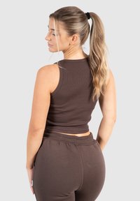 Brun ribbad tanktop med en kortad design, i kombination med matchande sweatpants. Har en jämn textur och en enkel silhuett.