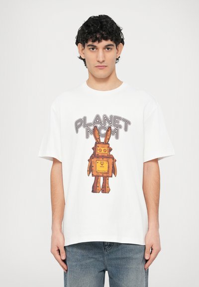 T-shirt en coton blanc avec un grand imprimé graphique représentant un robot semblable à un lapin brun avec un corps carré jaune et le texte "PLANET MCM".