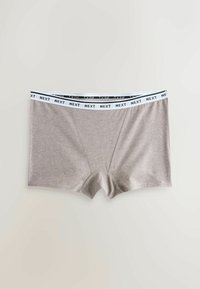 Caleçons gris avec une ceinture élastique blanche ornée du texte noir répété « NEXT », présentés à plat sur un fond clair.