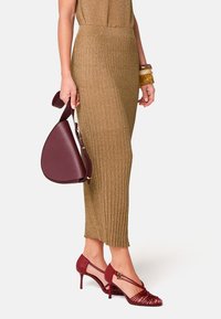 Strick, gold geripptes Midikleid; burgunderfarbene Lederhandtasche mit geschwungener Form; passende Riemchenabsätze mit spitzen Zehen und dekorativem Zubehör.