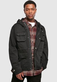 Black hooded jacket with multiple pockets, button accent, and a zip closure, layered over a red and black plaid shirt. Smooth texture.