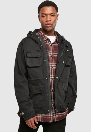 Black hooded jacket with multiple pockets, button accent, and a zip closure, layered over a red and black plaid shirt. Smooth texture.