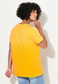 T-shirt jaune vif à manches courtes et col rond. Texture douce, coupe décontractée et ourlet droit, associé à un jean bleu clair.
