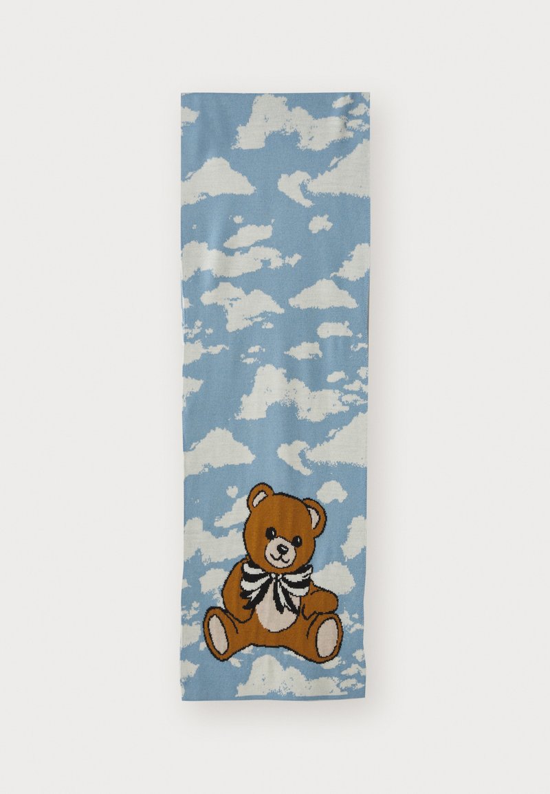 Cachecol azul com padrões de nuvens brancas e um urso de pelúcia castanho, usando um laço preto e branco, sentado na parte inferior.
