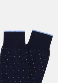 Calcetines navy hechos de una tela suave con pequeños lunares azul claro. Presentan un puño acanalado azul claro y una textura lisa.