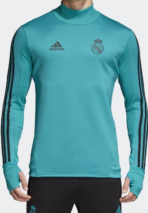 Maglietta sportiva a maniche lunghe di colore teal con colletto alto. Presenta il logo Adidas nero e il crest del Real Madrid, con tre strisce nere sulle maniche.