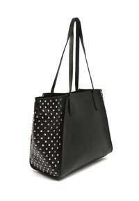 Sac tote noir en cuir synthétique avec des bretelles plates, présentant des accents cloutés argentés d'un côté et une surface lisse de l'autre.