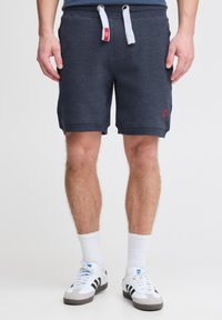 Mörkgrå shorts i mjukt, strukturerat tyg, med dragsko i midjan och en liten röd logotyp på vänster ben.