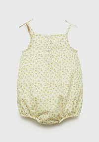 Cvečna igračka iz svetlo rumene tkanine z majhnimi zelenimi in belimi cvetovi. Ima nastavljive naramnice in tri gumbe spredaj.