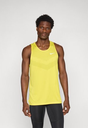 Kollane Nike'i tank top, mille ülemises osas on tekstuuriga geomeetriline muster ja ümar kaelus, koos mustade spordilegging'itega.