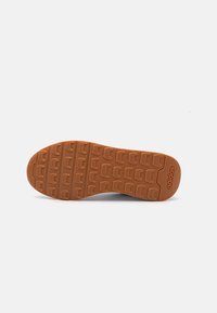 Semelle en caoutchouc avec un motif de grip texturé en marron. Présente le logo de la marque embossé au niveau du talon et un design à bout arrondi.