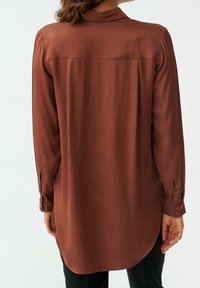 Brown, long-sleeved shirt made of smooth fabric with a collar, buttoned cuffs, and a rounded hem at the back.