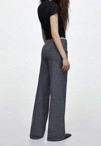 Pantalon à jambes larges gris foncé, en mélange de laine sur mesure, avec une taille haute, une poche arrière unique et une texture lisse.
