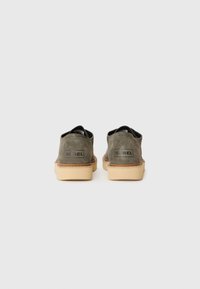 Green suede shoes with a round toe and rubber outsole. Features branding on the heel and contrasting beige midsole. Low-cut design.