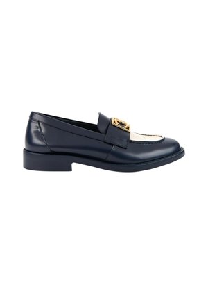 Mocassin en cuir noir et blanc avec un petit talon et une boucle décorative dorée sur la bride du dessus.