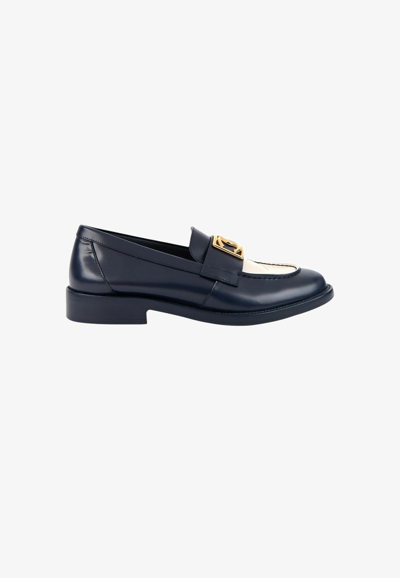 Mocassin en cuir noir et blanc avec un petit talon et une boucle décorative dorée sur la bride du dessus.