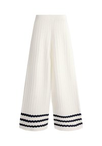 Pantalon en maille blanc à jambes larges avec motif ondulé texturé et trois bandes horizontales noires près de l'ourlet sur chaque jambe.