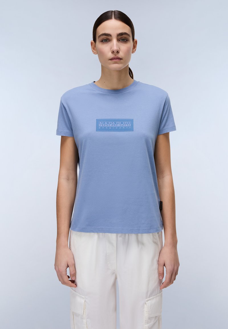 Blå bomulds t-shirt med korte ærmer, med et rektangulært logo i en lysere nuance. Den har en afslappet pasform og en rund halsudskæring.