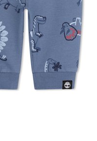 Blauwe katoenen joggingbroek met dinosaurussenprints in verschillende kleuren. Voorzien van ribgebreide manchetten en een zwart logo-label aan de zoom.