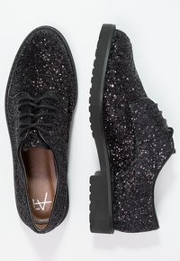 Chaussures Oxford noires pailletées avec dessus texturé, semelle en caoutchouc noire plate et design traditionnel à lacets. Intérieur avec doublure marron.