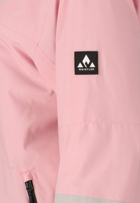 Helle rosa wasserdichte Jacke mit einem schwarzen "Whistler"-Logo-Patch, Reißverschlusstaschen und einem schlanken Design. Weiche Textur.