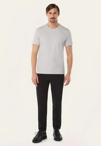 Grijze katoenen T-shirt met een ronde halslijn, korte mouwen, gecombineerd met zwarte slim-fit broeken en zwarte veterschoenen.
