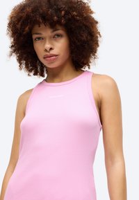 Ανοιχτό ροζ ριπ tank top με στρογγυλή λαιμόκοψη. Διαθέτει ένα μικρό λευκό λογότυπο "Calvin Klein" στο στήθος. Λείος ύφασμα και εφαρμοστό σχέδιο.